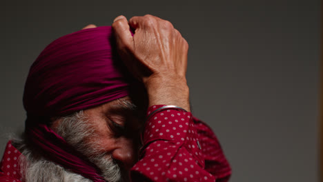 Close-Up-Low-Key-Studio-Lighting-Shot-Of-Senior-Sikh-Man-With-Beard-Tying-Fabric-For-Turban-Against-Dark-Background-5